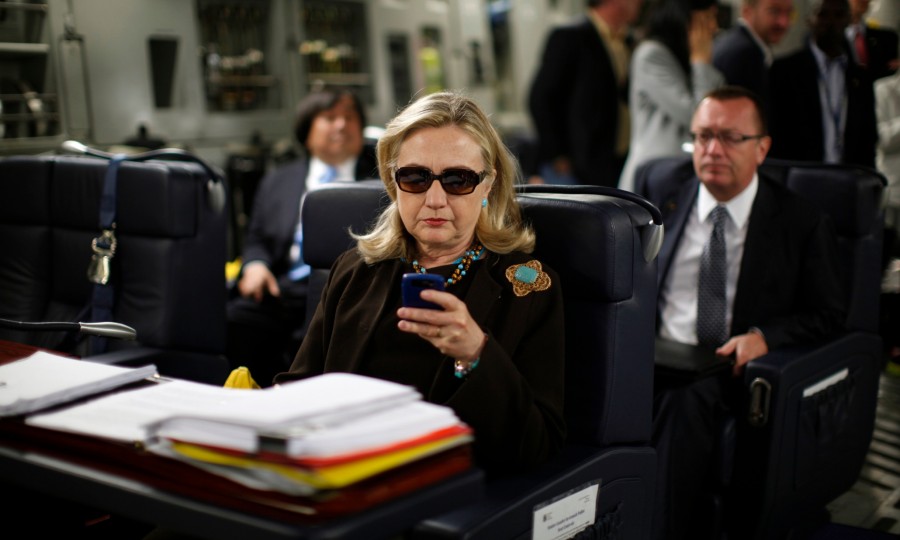 FILE - In this Oct. 18, 2011, file photo, then-Secretary of State Hillary Rodham Clinton works from a desk inside a C-17 military plane upon her departure from Malta, in the Mediterranean Sea, bound for Tripoli, Libya. Clinton has joined Twitter, describing herself as a "pantsuit aficionado" and a "hair icon." The potential 2016 presidential candidate's profile page shows the infamous photo of the stern-looking Clinton wearing dark sunglasses and reading her Blackberry. (AP Photo / Kevin Lamarque, Pool, File)