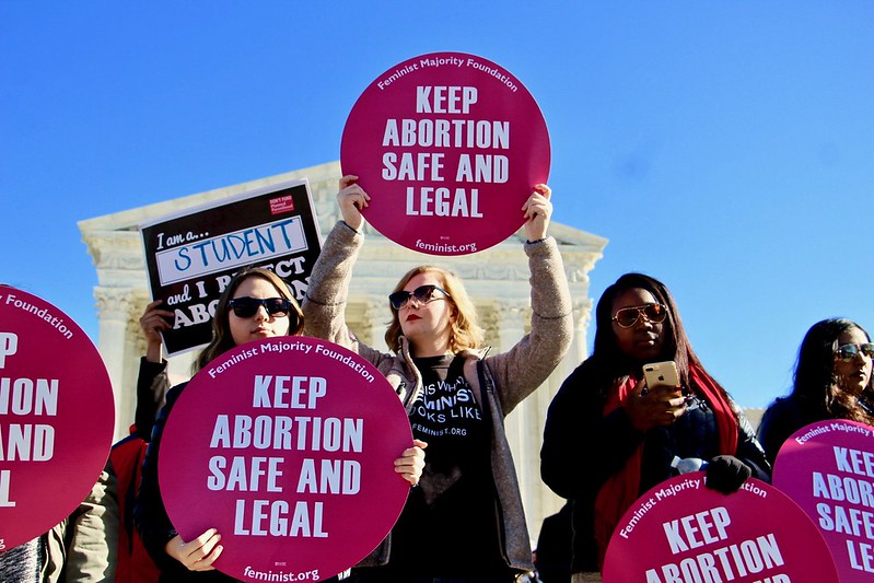 Women holding signs expressing their thoughts. "Keep abortion safe and legal."