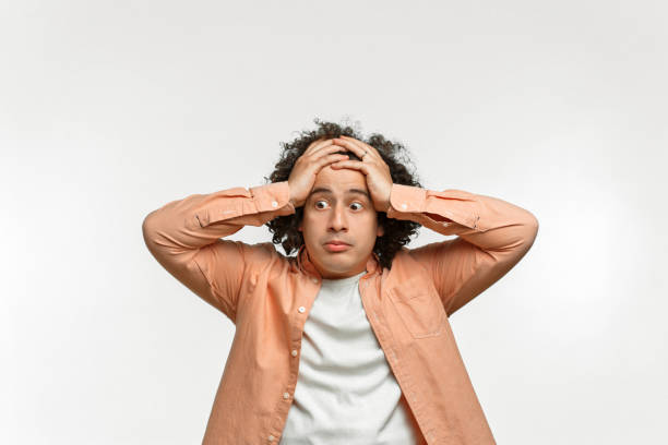 Isolated emotional portrait of a man with curly brown hair. He grabbed his head in amazement, bulging eyes and looking into the camera