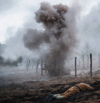 Unrecognizable male soldier laying on battle field,
around the body there is a blast from a mine.