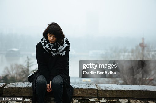 Girl sitting on a wall and having a tough time