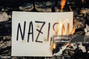 The word Nazism on white paper burning in a flame of fire. The concept of discrimination and problem of fascism