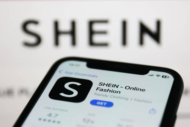 Shein on App Store displayed on a phone screen and Shein website displayed on a screen in the background are seen in this illustration photo taken in Krakow, Poland on January 19, 2023. (Photo by Jakub Porzycki/NurPhoto via Getty Images)