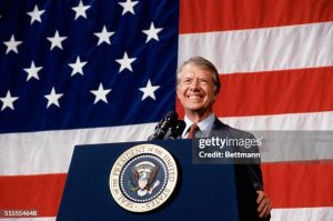 (Original Caption) 3/24/1979-Elk City, Oklahoma: President Jimmy Carter addressing a town meeting. American flag is hung in background.