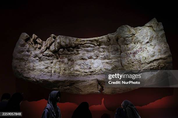 A replica of a figurative cave painting originating from South Sulawesi is displayed at the National Museum in Jakarta, Indonesia, on December 28, 2025. Art first appears on the surfaces of hard rock walls in the form of paintings, engravings, and carvings, collectively known as rock art. In general, the depicted forms include hand stencils, human figures, animals, and geometric lines. The oldest rock art in Indonesia emerges long before modern humans in Europe begin expressing themselves through paintings on cave walls and cliffs. Based on uranium-series dating, these paintings are approximately 51,200 years old. (Photo by Agoes Rudianto/NurPhoto via Getty Images)