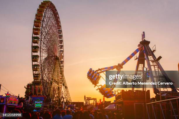 ferris wheel and attraction in amusement park at sunset